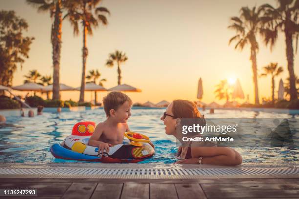 bambino con madre in piscina, località di villeggiatura - vacanze foto e immagini stock