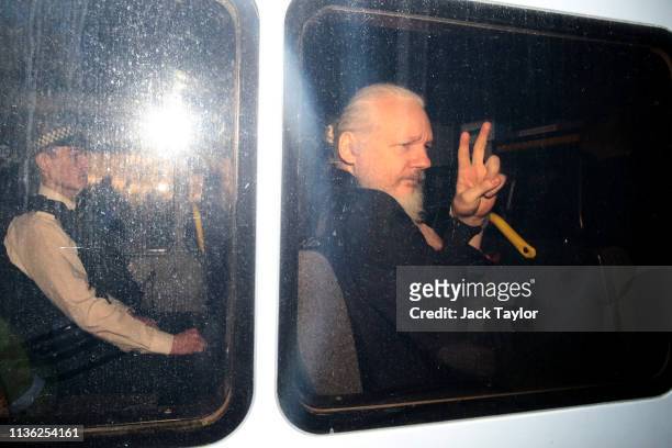 Julian Assange gestures to the media from a police vehicle on his arrival at Westminster Magistrates court on April 11, 2019 in London, England....