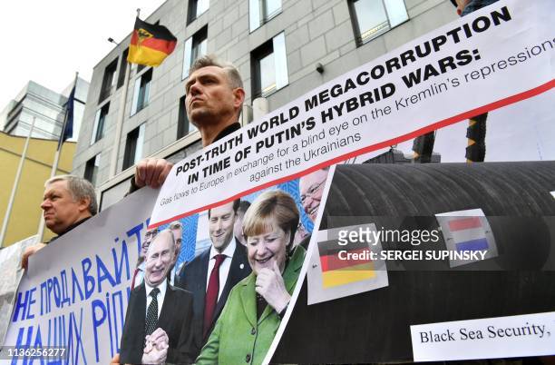 Relatives of Ukrainian political prisoners and human rights activists hold a placard depicting Russian President Vladimir Putin and German Chancellor...