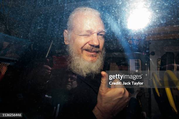 Julian Assange gestures to the media from a police vehicle on his arrival at Westminster Magistrates court on April 11, 2019 in London, England....