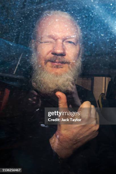 Julian Assange gestures to the media from a police vehicle on his arrival at Westminster Magistrates court on April 11, 2019 in London, England....