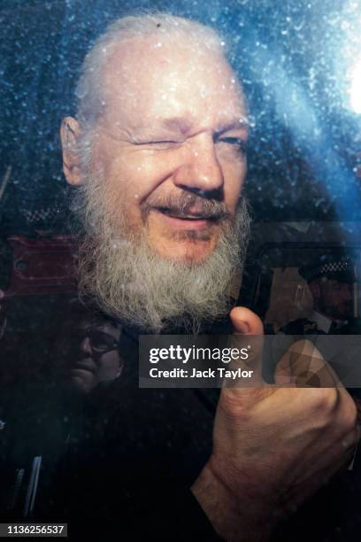 Julian Assange gestures to the media from a police vehicle on his arrival at Westminster Magistrates court on April 11, 2019 in London, England....