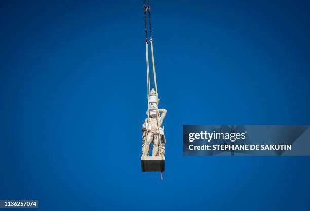 Crane lifts one of the restored genies and angels sculptures during their re-installation on the dome of the Notre-Dame du Val-de-Grace church in...