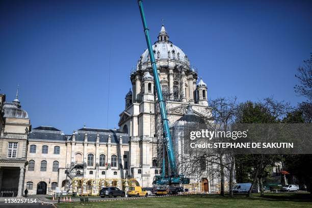 Crane lifts one of the restored genies and angels sculptures during their re-installation on the dome of the Notre-Dame du Val-de-Grace church in...