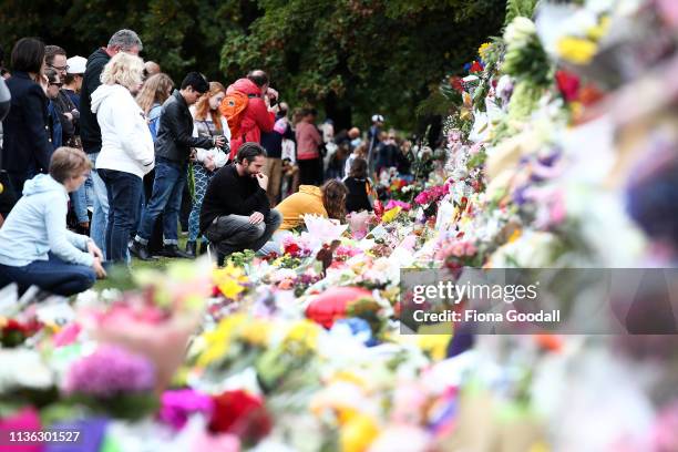 People lay flowers and spend time at the wall of flowers at the Botanic Gardens on March 17, 2019 in Christchurch, New Zealand. 50 people are...