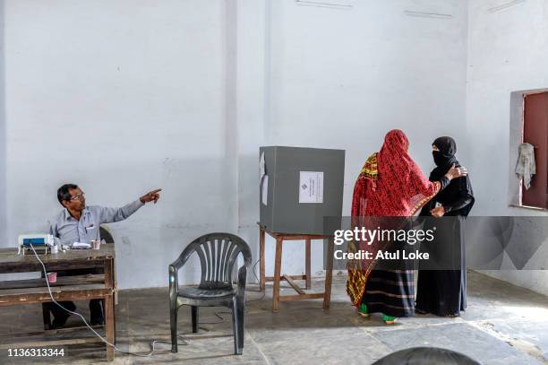 An Indian Muslim woman helps an eldery lady to get to voting machine at a polling station on April 11, 2019 in Muzzafarnagar, Utter Pradesh, India....