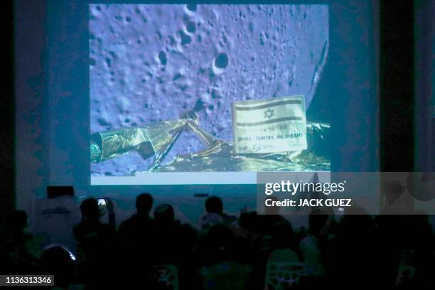 People watch a screen showing a picture taken by the camera of the Israel Beresheet spacecraft of the moon surface as the craft approaches and before...