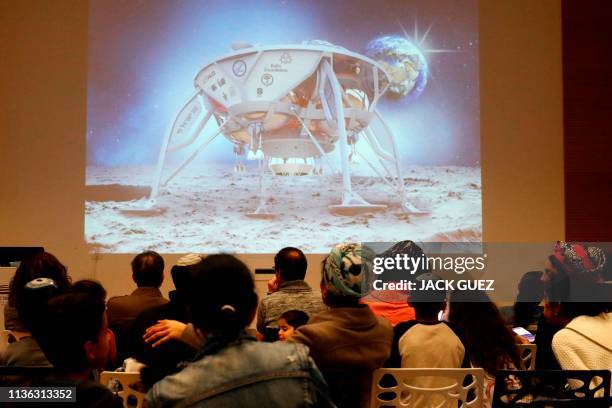 People watch a screen showing explanations of the landing of Israeli spacecraft, Beresheet's, at the Planetaya Planetarium in the Israeli city of...