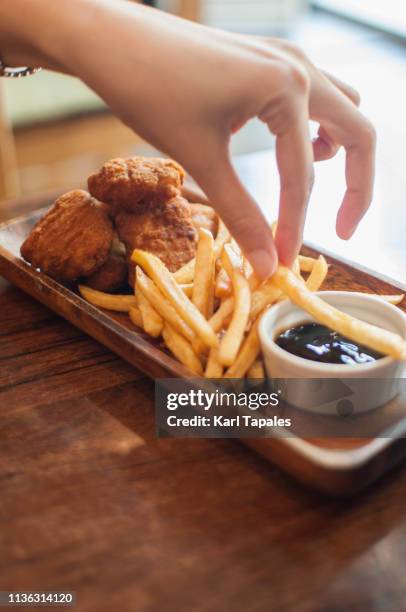 chicken nuggets and fries on a wooden table - eating nuggets stockfoto's en -beelden