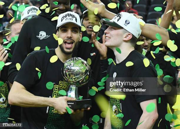 Ehab Amin and Payton Pritchard of the Oregon Ducks celebrate with the trophy after the team's 68-48 victory over the Washington Huskies to win the...