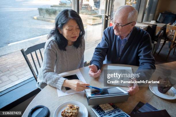 asian woman, senior man reviewing financial information on digital tablet - vancouver canada 2019 stock pictures, royalty-free photos & images