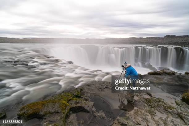 a lady taking photos of selfoss waterfall, north iceland - dettifoss waterfall foto e immagini stock