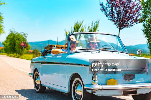 pareja madura en un viaje por carretera con un coche de época - convertible fotografías e imágenes de stock