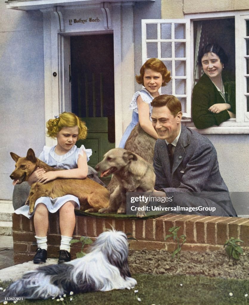 George VI with his daughters and their pet dogs outside Y Bwthyn Bach (The Little House) the gift of the Welsh people to Princess Elizabeth (standing by window). Princes Margaret seated, Queen Elizabeth looks on from inside cottage...