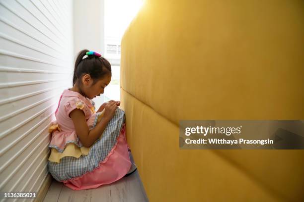 children who are upset by having their heads in their hands sitting on the concept behind the sofa to bully stress, depression or frustration. - children violence stock pictures, royalty-free photos & images