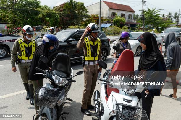 Traffic police check travellers at a checkpoint along a main road of Narathiwat to implement road safety for motorists as Thai people travel to their...