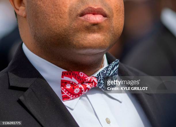 Man wearing a bow tie with the colors of two rival Los Angeles gangs, The Bloods and Crips, attends the procession route for Nipsey Hussle after his...