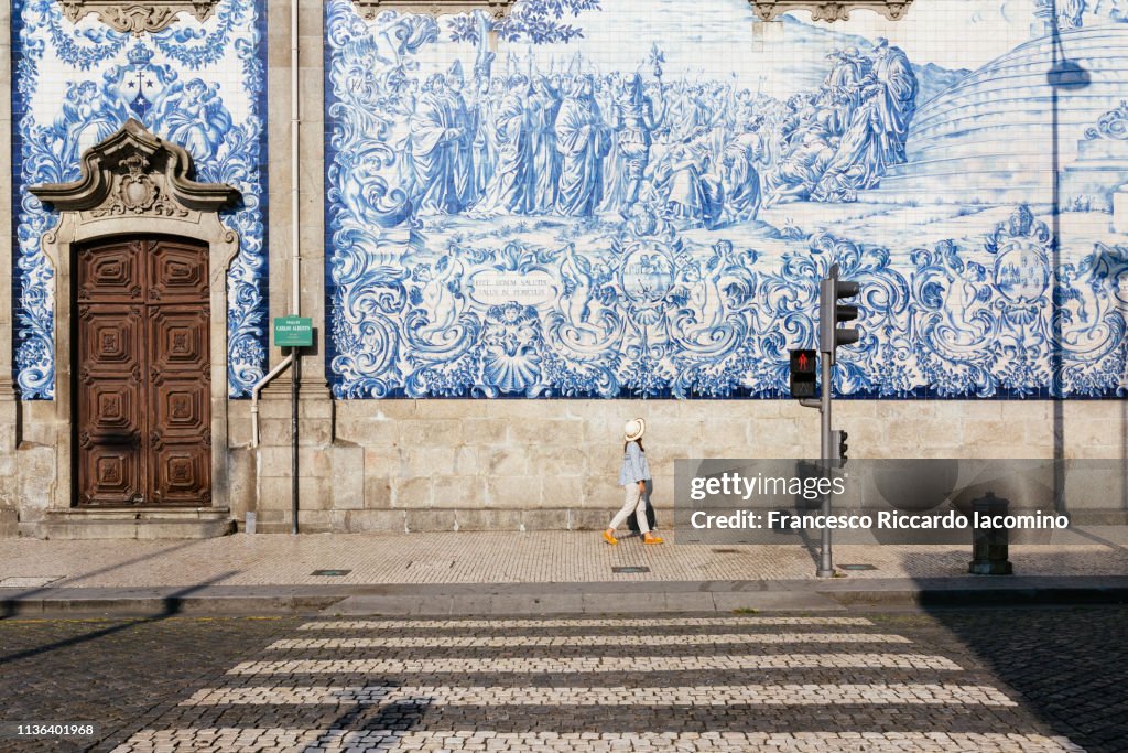 Girl walking in Porto, azulejos wall in background