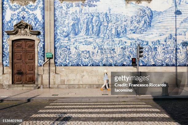 girl walking in porto, azulejos wall in background - cultura portoghese foto e immagini stock