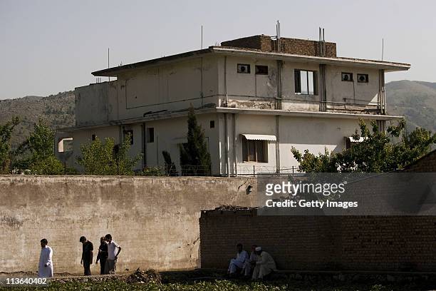 People walk past Osama Bin Laden's compound, where he was killed during a raid by U.S. Special forces, May 3, 2011 in Abottabad, Pakistan. Bin Laden...