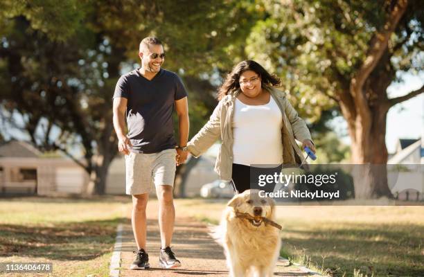 couple walking dog in park - animal behavior stock-fotos und bilder