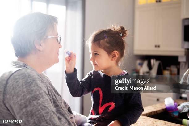 sweet little girl put lipstick to her grandmother - showus makeup stock pictures, royalty-free photos & images