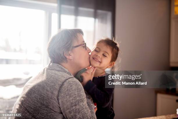 grandmother give a kiss to her sweet granddaughter - chubby granny foto e immagini stock