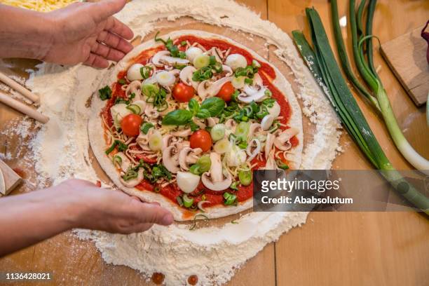 close-up of woman's hands preparing vegetarian pizza at home - vegetarian pizza stock pictures, royalty-free photos & images