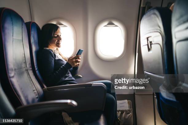 using phone on an airplane ride - seat stock pictures, royalty-free photos & images