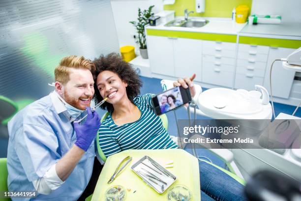 furchtlose patientin, die zahnophobie überwindet, ein selfie mit ihrem zahnarzt nimmt, bevor sie eine betäubungsspritze mit einer spritze erhält - dentist phobia stock-fotos und bilder