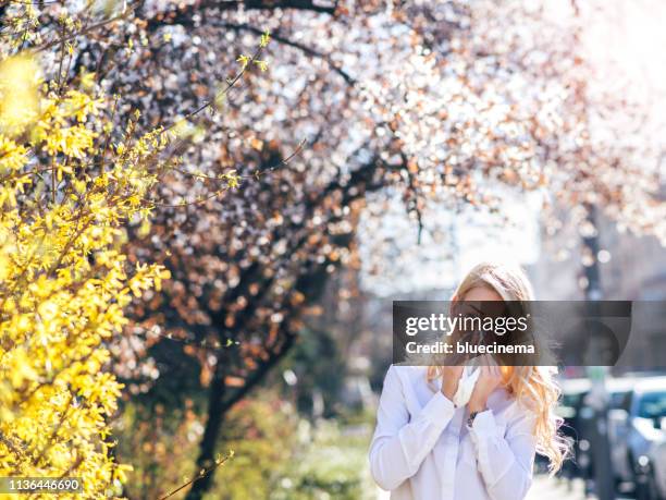 woman sneezing in the blossoming garden - spring allergies stock pictures, royalty-free photos & images