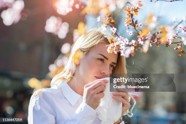 vrouw niezen in de bloeiende tuin - hayfever stockfoto's en -beelden