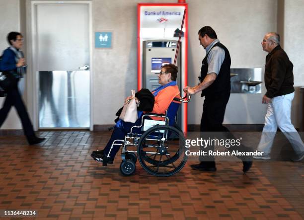 An elderly Southwest Airlines passenger needing assistance is pushed through the terminal in a wheelchair supplied by the airline company at...