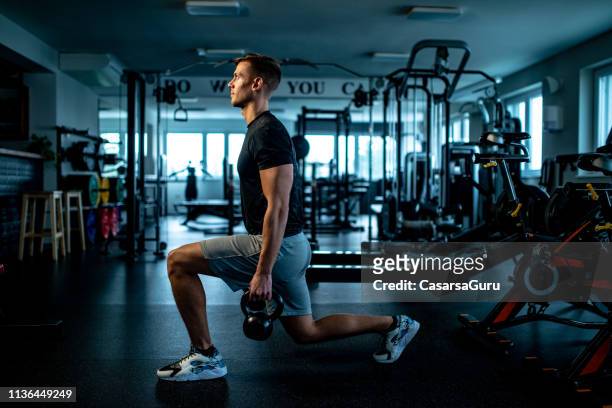 young man practicing walking lunge with kettle bell - lunge imagens e fotografias de stock
