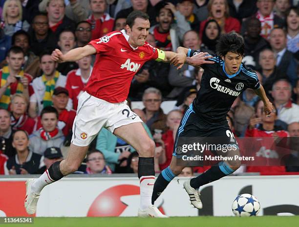 John O'Shea of Manchester United clashes with Atsuto Uchida of Schalke 04 during the UEFA Champions League Semi-Final second leg match between...