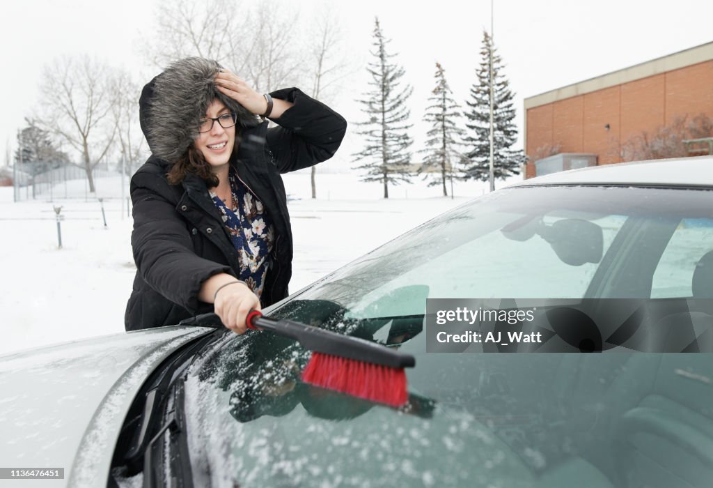 Sweeping snow off her car window