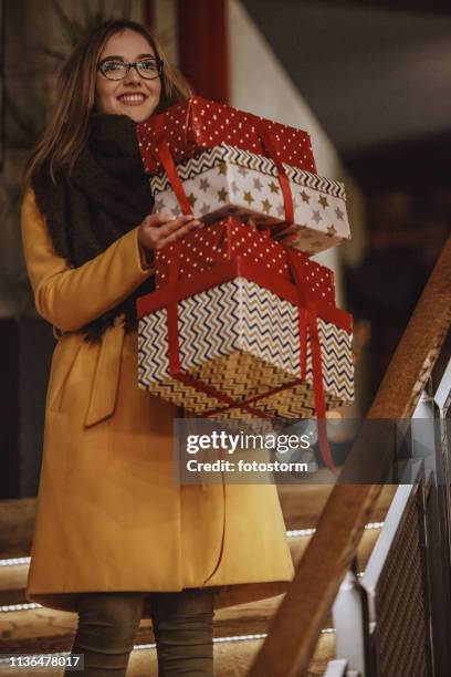 smiling woman carrying christmas presents - carrying gifts stock pictures, royalty-free photos & images