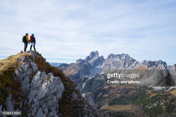 two hikers standing together high up with amazing view mountain range - two people hiking stock pictures, royalty-free photos & images