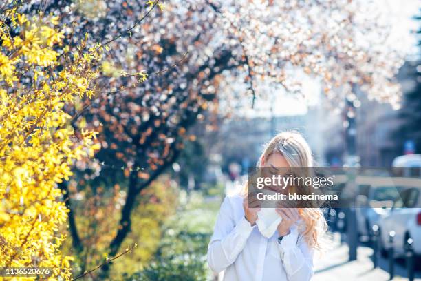 vrouw niezen in de bloeiende tuin - hayfever stockfoto's en -beelden