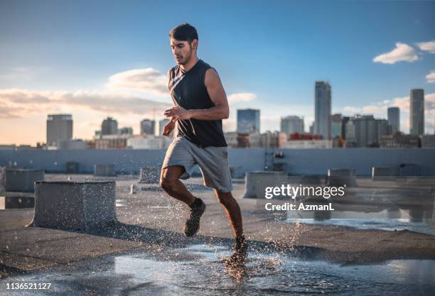 determined sporty young man jogging on terrace - young man jogging stock pictures, royalty-free photos & images