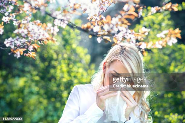 vrouw niezen in de bloeiende tuin - hayfever stockfoto's en -beelden