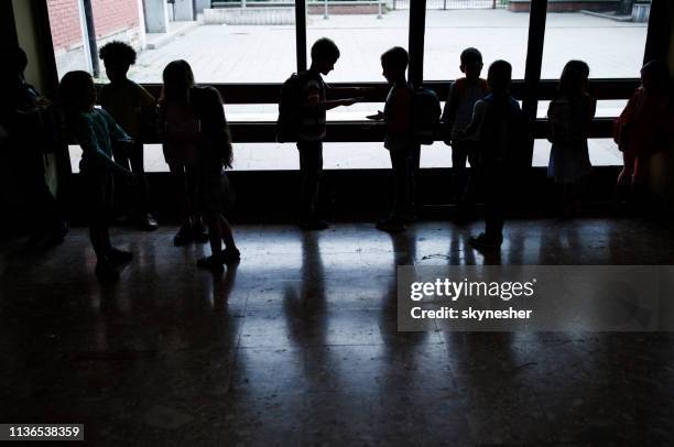 silhouettes of large group of elementary students in a hallway. - school building silhouette stock pictures, royalty-free photos & images