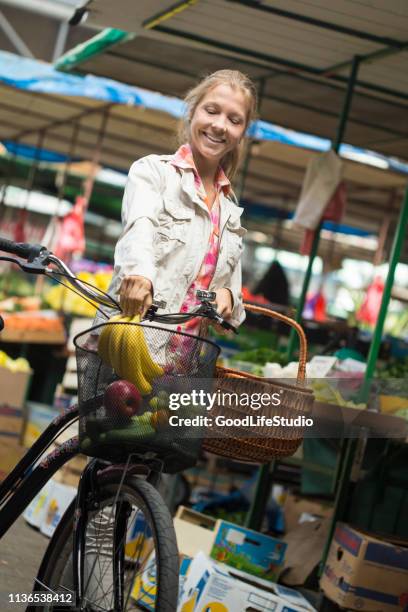 junge frau kauft lebensmittel auf einem bauernmarkt - shopping with bike stock-fotos und bilder