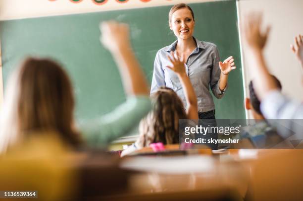 happy elementary teacher asked a question on a class at school. - elementary school building stock pictures, royalty-free photos & images