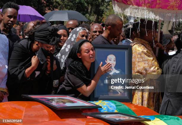 Woman cradles a photo and cries over the coffin of her loved one during a memorial service for the Ethiopian passengers and crew who perished in the...