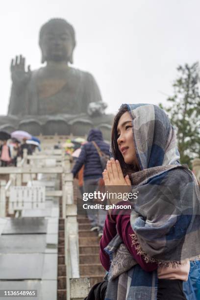 asiatischer tourist, der tian tan buddha auf der insel ngong pinglantau, hong kong, besucht, verehrt an regendem tag. der große buddha ist eine große bronzestatue von buddha shakyamuni, einem der meistbesuchten reiseziele in hk - großer buddha stock-fotos und bilder