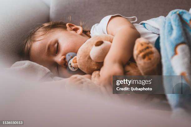 bébé garçon dormant avec l'ours de nounours et la sucette - bébé doudou photos et images de collection