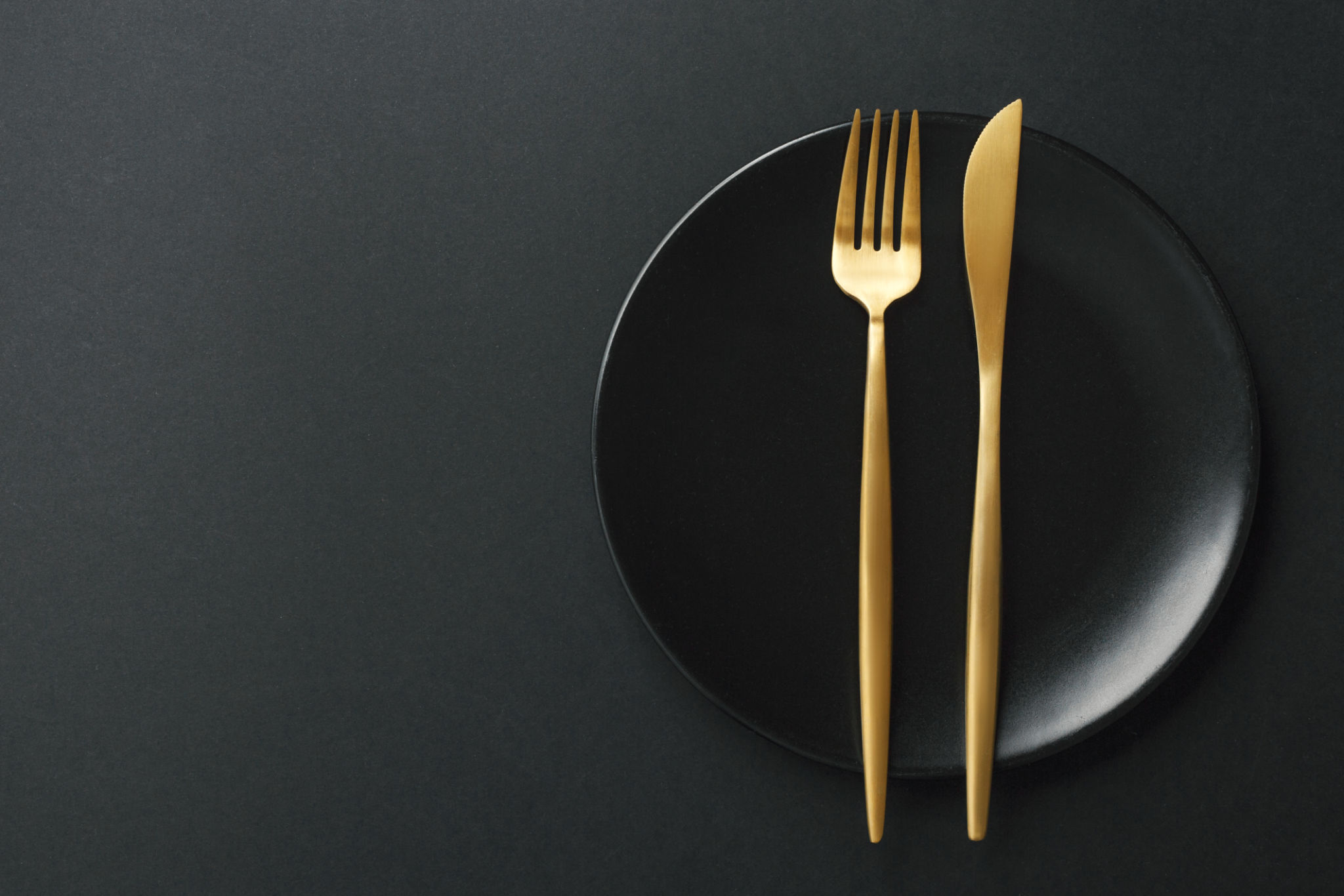 Gold cutlery set on black background Gold cutlery set on black background