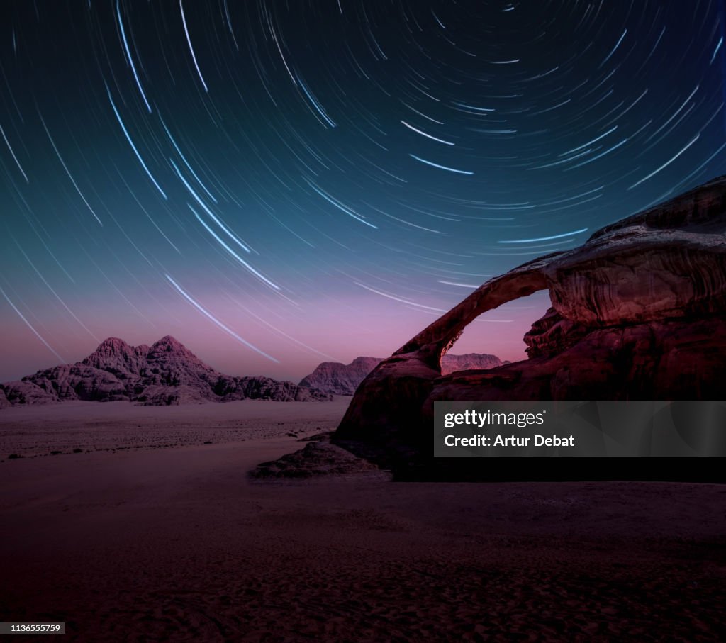 Long exposure of the stars in the Wadi Rum desert of Jordan with natural arch.
