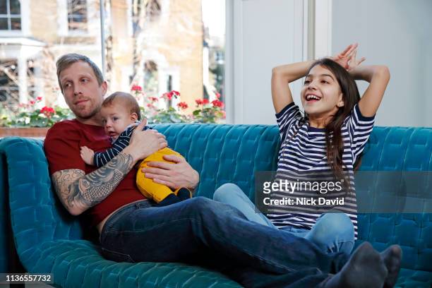 Mixed race girl sitting on sofa with father and baby brother